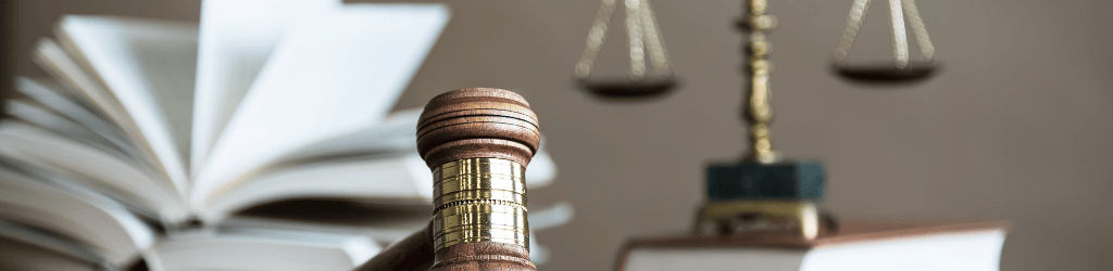 Law book, gavel, and scales of justice on a desk.