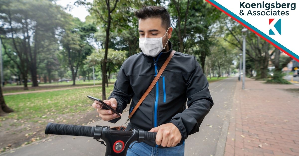 Man in mask on e-scooter checks phone
