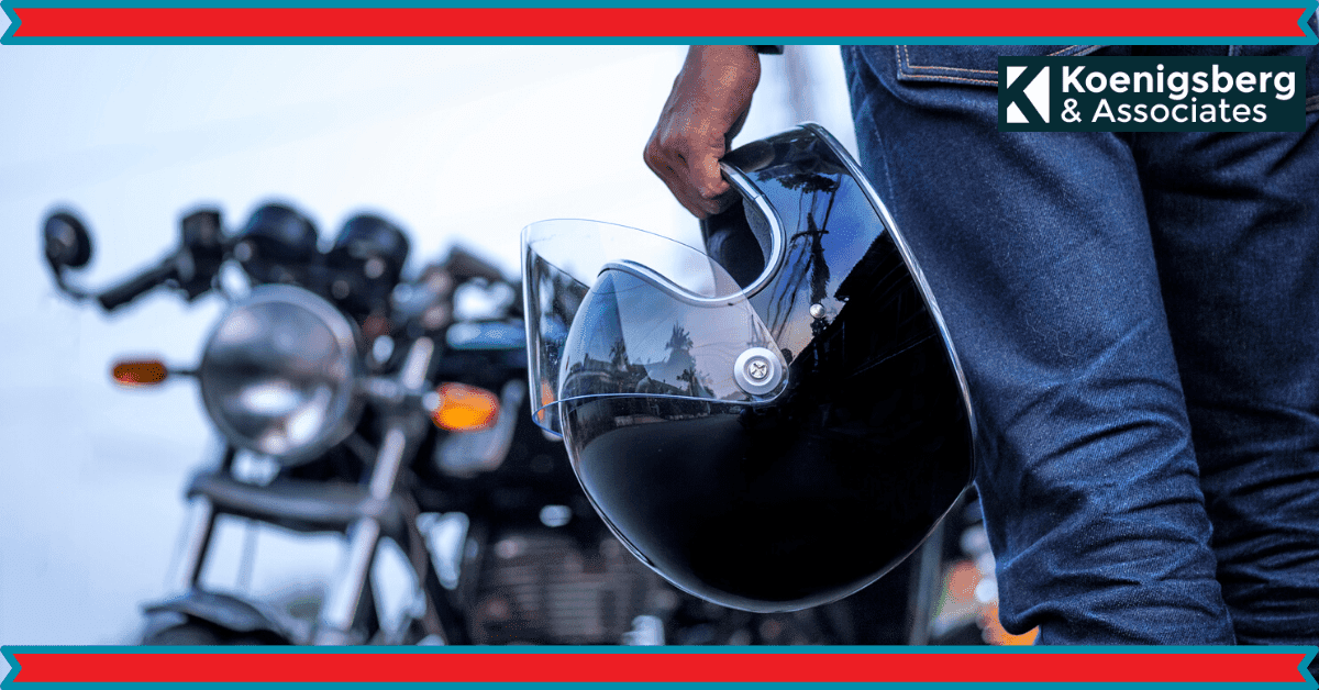 Motorcyclist holding helmet next to motorcycle