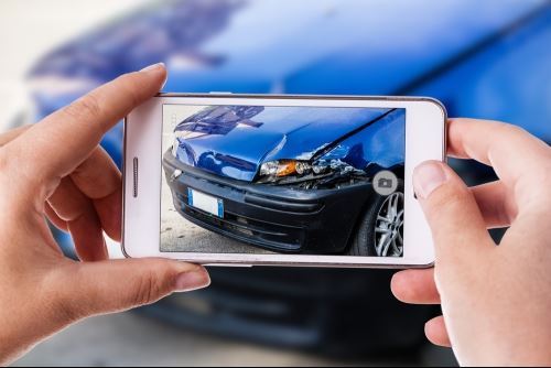 Lady taking picture of damaged car