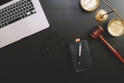 notebook, glasses, gavel, and laptop on a desk