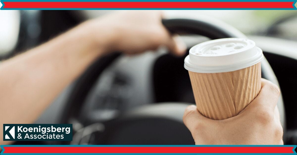 Man holding a cup of coffee while driving