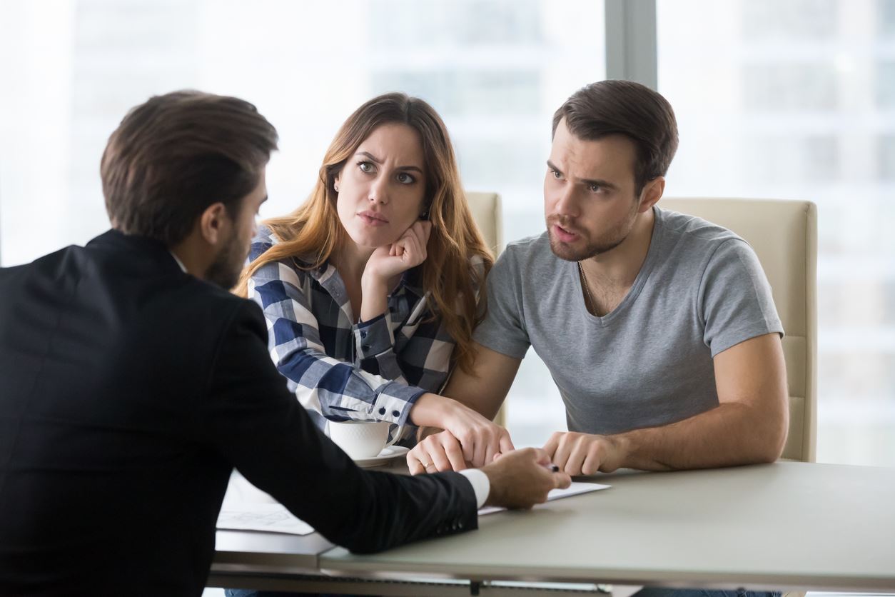 Angry dissatisfied couple arguing meeting lawyer or manager having legal fight complaints on bad client service, annoyed mad customers claiming change in contract terms demanding fraud compensation (Angry dissatisfied couple arguing meeting lawyer or