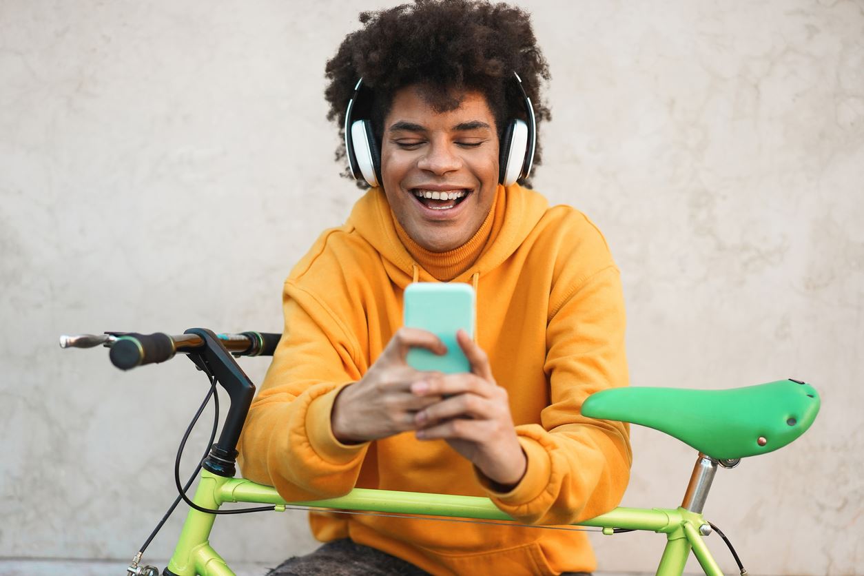 Happy african millennial guy listening music playlist with smartphone app outdoor - Young man having fun with technology trends - Tech, generation z and stylish concept - Focus on face (Happy african millennial guy listening music playlist with smartphone