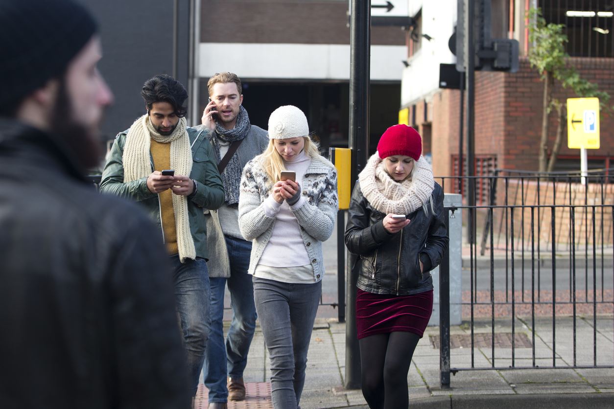 Pedestrians distracted with their phones as they cross the street