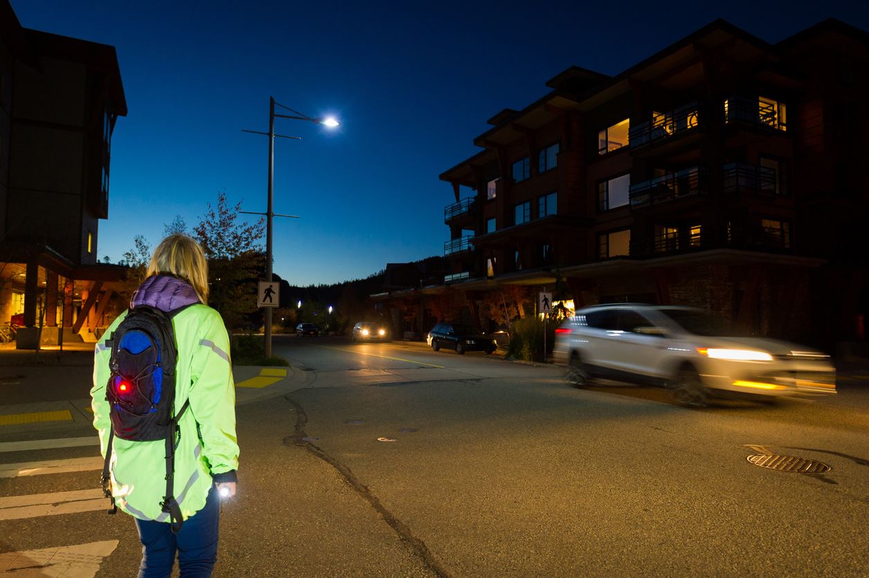 Pedestrian in high visibility clothes crossing street at night