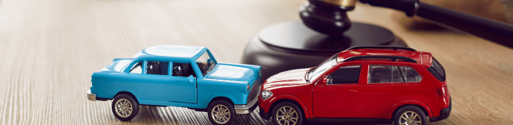 Car Accident Attorney A blue toy truck, and a red toy car, in an accident on a lawyer's desk.